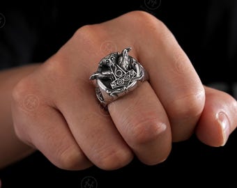 May include: A silver ring with a detailed Viking design. The ring features a hammer, a bird, and intricate patterns. The ring is worn on a hand against a dark background, highlighting the metallic sheen and craftsmanship.
