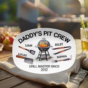 May include: White oval platter with the text "DADDY'S PIT CREW" and a grill illustration. Includes names Liam, Lucas, Riley, and Sophia. The text "GRILL MASTER SINCE 2012" is also present.