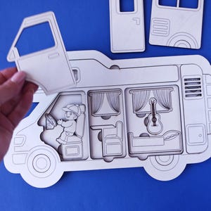 May include: A white wooden camper van puzzle with removable pieces, including a door, windows, and interior details like a bed, guitar, and driver. The puzzle is set against a blue background.
