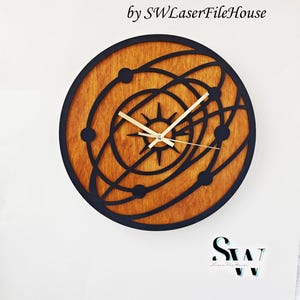 May include: A circular laser cut wooden wall clock featuring a black outer frame and a natural wood grain centre. The design depicts a celestial orbital pattern with a central star and gold-coloured clock hands. Text reads: Laser Cut Wooden Wall Clock by SWLaserFileHouse. SVG - AI - CDR - DXF - EPS - PDF - PNG - Lightburn.