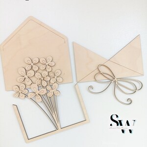 May include: Digital Download Laser File. SVG CDR AI DXF EPS PDF Lightburn. Laser-cut light wood pieces including an envelope with a flower bouquet cutout, a separate envelope flap, and a decorative bow. The logo SW Laser Arts House is visible.