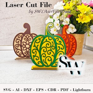 May include: Three laser-cut wooden pumpkin decorations in brown, orange, and green with intricate designs. The pumpkins are displayed in front of a vase of flowers. Text on the image reads "Laser Cut File" and "by SWLaserFileHouse."