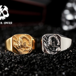 May include: Two silver and gold rings with a scorpion design. The rings are on a black background.  THUNDER CHOICE is written in white text on a black background.