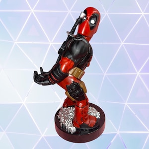 May include: A Deadpool figurine in a red and black suit with a katana strapped to the back. The character is posed with hands extended forward as if holding an object, wearing a brown utility belt and holster, standing on a circular base.