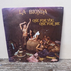 Op de afbeelding: Een vintage vinyl platenhoes met een band genaamd "La Bionda" met de titel "One For You, One For Me". De hoes toont een groep mensen in een setting die doet denken aan een feest met een Midden-Oosters of Arabisch thema.