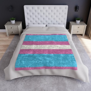 Könnte beinhalten: Ein weißes Bett mit einer hellblauen, weißen und rosafarbenen gestreiften Bettdecke. Die Bettdecke hat einen abgenutzten, Vintage-Look. Das Bett steht in einem Schlafzimmer mit einer dunkelgrauen Wand und zwei Holz-Nachttischen.