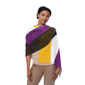 Peut inclure: Une personne portant une écharpe rayée violette, noire, blanche et jaune. L'écharpe est une représentation du drapeau de la fierté non binaire.