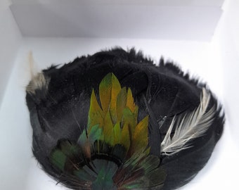 Pasador con plumas negras y verdes.