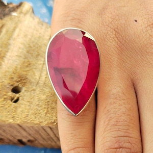 Op de afbeelding: Een ring met een dieprode, peervormige edelsteen, gezet in zilver.