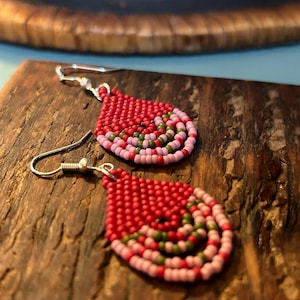 Puede incluir: Un par de pendientes en forma de lágrima hechos con cuentas rojas, rosas y verdes. Los pendientes tienen ganchos plateados.
