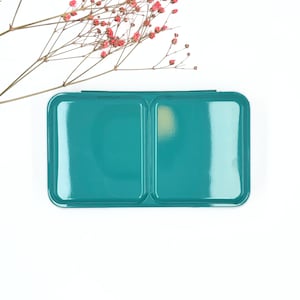 Può includere: Una tavolozza di vernice in metallo blu turchese con due sezioni. La tavolozza è vuota e pronta per l'uso.