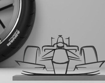 May include: A black and white silhouette of a racing car, viewed from the front, is displayed on a grey platform. The car is a stylised outline with no details.