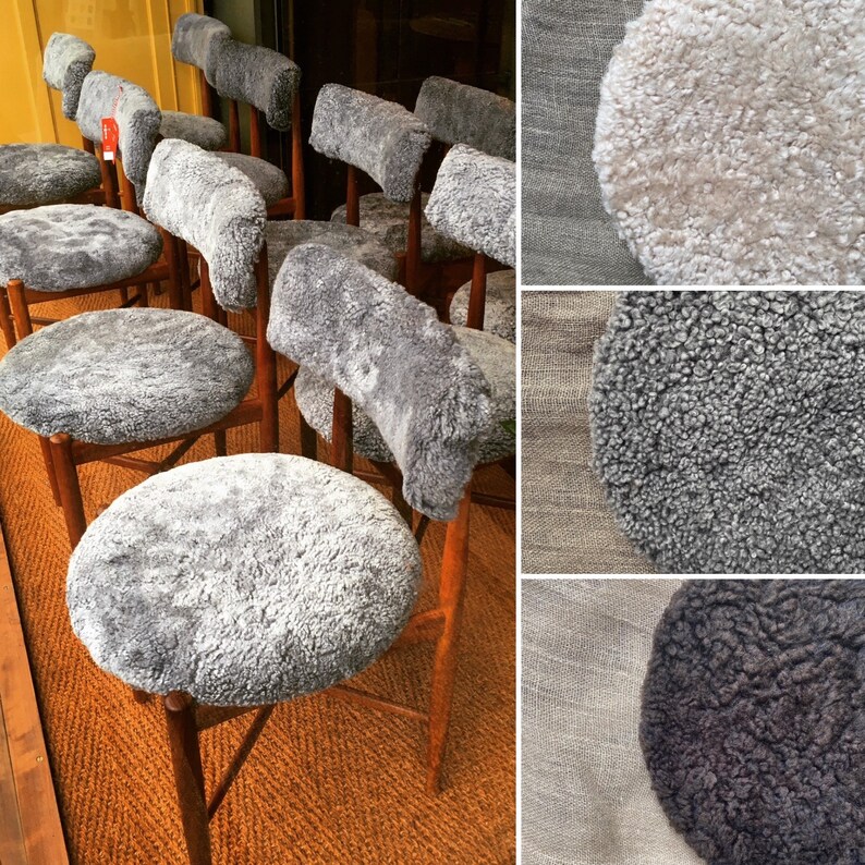 May include: A set of six chairs with gray sheepskin seat cushions and wooden legs. The chairs are arranged in a row, with the seat cushions facing the viewer. The chairs are in a room with a wooden floor and a wall with a wooden panel.