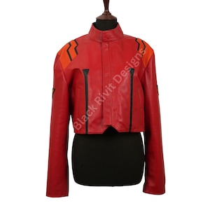 May include: A red cropped jacket with orange and black accents. The jacket has a stand-up collar and long sleeves. The shoulders feature orange and black geometric designs. The text "Black Rivit Designs" is printed on the right side of the jacket.