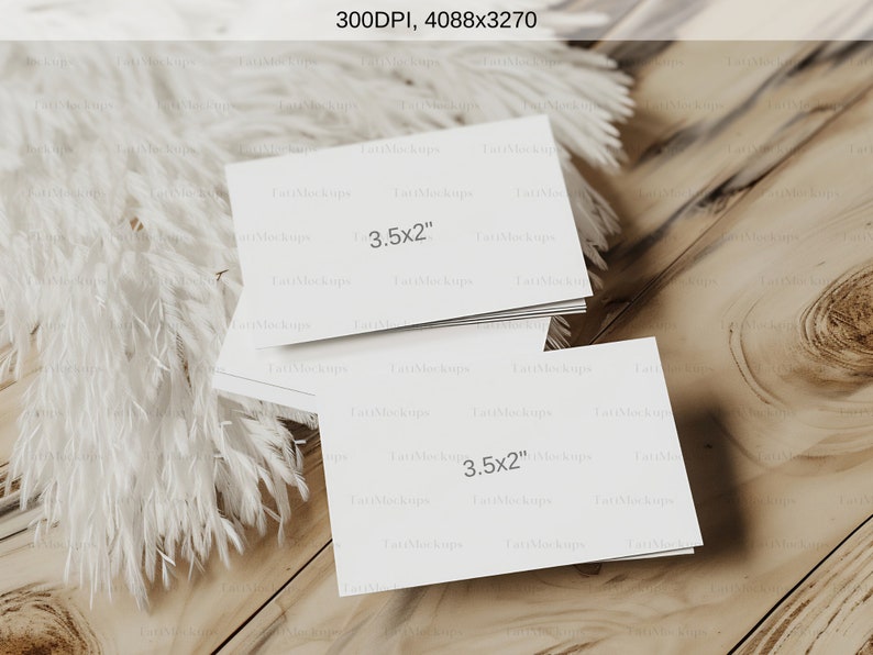 May include: A stack of white rectangular cards, each measuring 3.5 x 2 inches, rests on a light wood surface. Fluffy white decorative elements are arranged to the left. The image is well-lit, showcasing the cards' clean design.