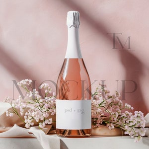 May include: A bottle of pink champagne with a white label that says "psd + jpg" on a pink background with white flowers and a white fabric.