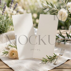 May include: Two vertical off-white rectangular cards standing upright on a light-colored fabric surface. The cards feature the word MOCKUP in large grey capital letters and the text psd + jpg in smaller letters. The cards are blank for custom design.