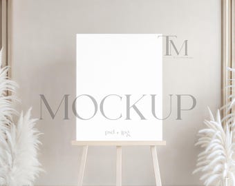 May include: A blank white canvas on a wooden easel, ideal for displaying artwork or designs. The word "MOCKUP" is displayed in a light gray font across the canvas. The background features neutral tones and decorative elements.