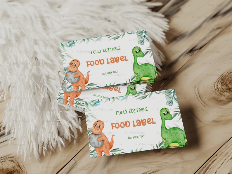 May include: A stack of fully editable food labels with a dinosaur theme. The labels feature illustrations of orange and green dinosaurs, with text that reads "FOOD LABEL" and "ADD YOUR TEXT". The labels are decorated with green foliage.