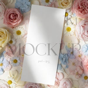May include: A vertical white card mockup with the word "MOCKUP" in gray, surrounded by a variety of pastel-colored flowers, including roses and daisies. The text "psd + jpg" is at the bottom of the card.