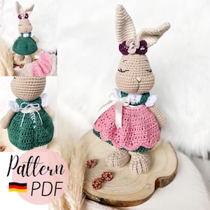 May include: A crocheted bunny doll wearing a pink and green dress with a white collar and a flower crown. The doll is beige with closed eyes and long ears. The image includes the text "Pattern PDF".