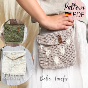 May include: A beige crocheted crossbody bag with white floral detailing. The bag features a flap closure and a small leather tag. The image also shows two other crocheted bags, one green and one cream-coloured, with different designs. Text on the image says "Pattern PDF" and "Boho Tasche".