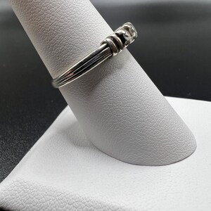 Op de afbeelding: Een zilveren ring met een getextureerde band en een klein, rond, zilveren accent.