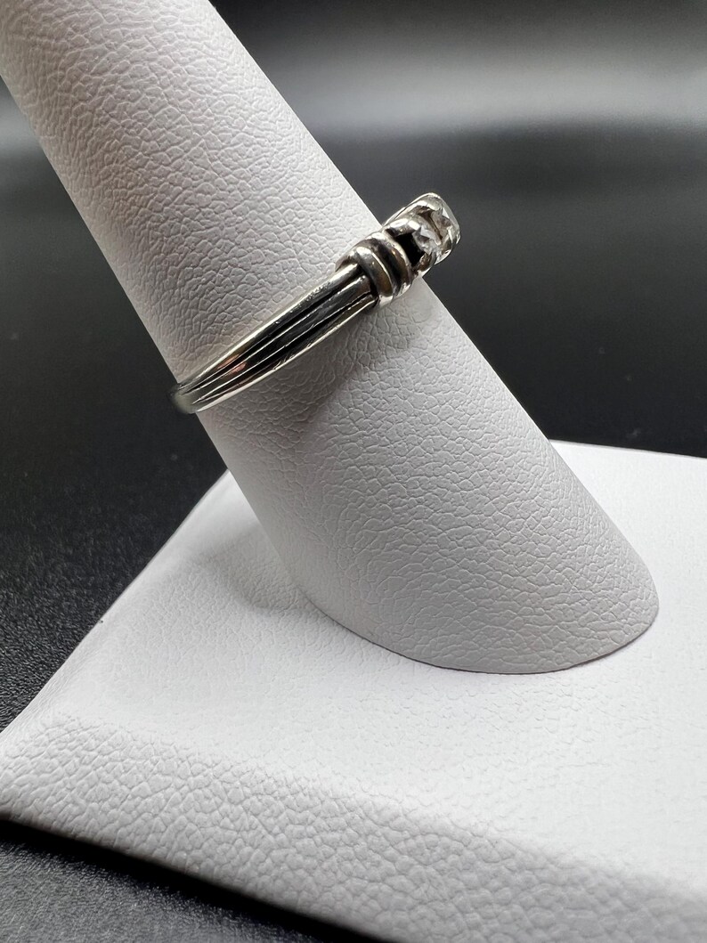 Op de afbeelding: Een zilveren ring met een getextureerde band en een klein, rond, zilveren accent.