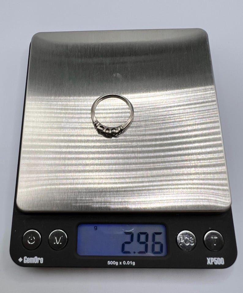 Op de afbeelding: Een zilveren ring met vijf kleine stenen op een digitale weegschaal die 2,96 gram aangeeft.