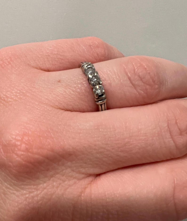 Op de afbeelding: Een zilveren bandring met vijf kleine ronde diamanten in een rij.