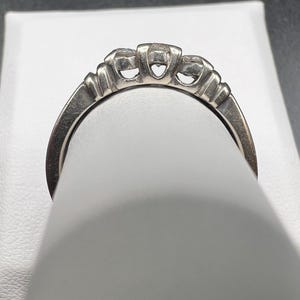 Op de afbeelding: Een zilveren ring met drie ronde diamanten in een kraalbezetting.