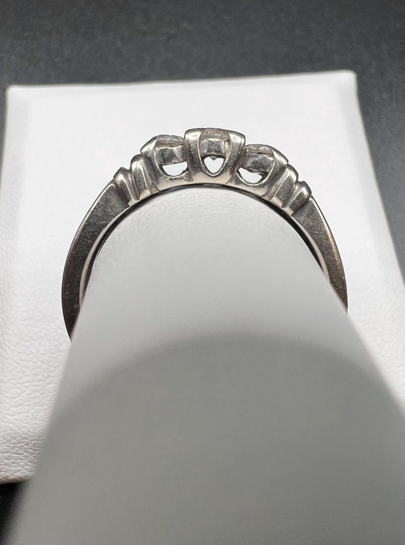 Op de afbeelding: Een zilveren ring met drie ronde diamanten in een kraalbezetting.