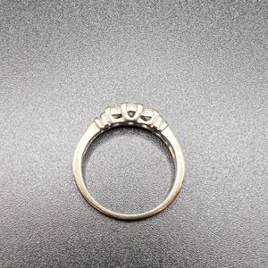 Op de afbeelding: Een zilveren ring met drie kleine diamanten in een kraalbezetting.