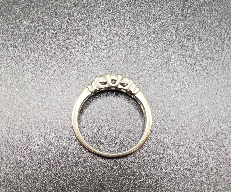Op de afbeelding: Een zilveren ring met drie kleine diamanten in een kraalbezetting.