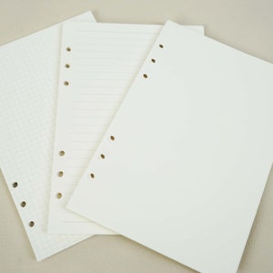 May include: Three white sheets of paper with punched holes along the side. The sheets are blank, but one has a grid pattern, one has lines, and one is plain.