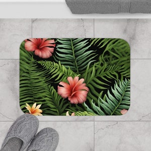 May include: A black bath mat with a tropical print featuring pink hibiscus flowers and green fern leaves.