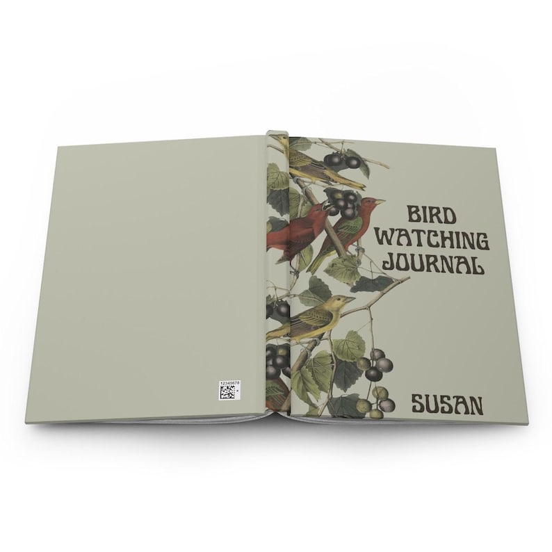 K&ouml;nnte beinhalten: Offenes Vogelbeobachtungsjournal mit hellgr&uuml;nem Einband. Die rechte Seite zeigt eine farbenfrohe Illustration von V&ouml;geln, Beeren und Bl&auml;ttern. Der Text "BIRD WATCHING JOURNAL" und der Name "SUSAN" sind auf dem Einband aufgedruckt.