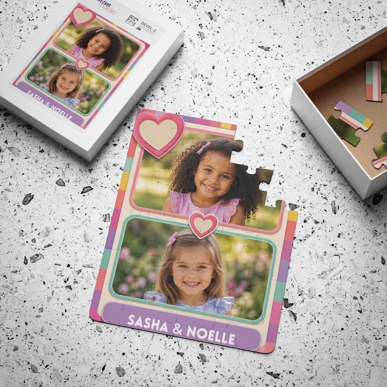 May include: A custom jigsaw puzzle featuring two rectangular photo frames with pink heart accents. The puzzle displays portraits of two young children and the text "SASHA & NOELLE" printed in white on a purple banner at the bottom of the puzzle.