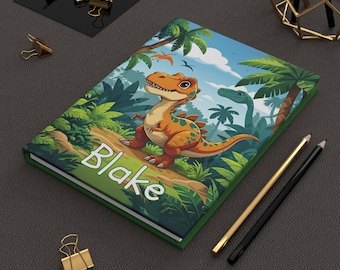 Könnte beinhalten: Ein Hardcover-Notizbuch mit einer farbenfrohen Illustration eines Cartoon-Dinosauriers in einer Dschungelkulisse. Das Notizbuchcover trägt den Namen "Blake" in weißen Buchstaben. Palmen und ein blauer Himmel sind im Hintergrund.