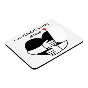 May include: White mouse pad with a black heart and two hands hugging it. The text "I am ALWAYS worthy of love" is printed on the mouse pad.