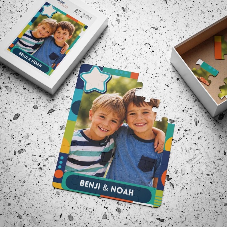 May include: A custom jigsaw puzzle featuring a photograph of two young boys, Benji and Noah, with a colorful border and a star icon. The puzzle is partially assembled, with the box lid showing the same image and the text Benji & Noah printed below.