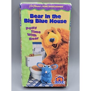 Puede incluir: Una cinta VHS de "Bear in the Big Blue House: Potty Time With Bear". La portada presenta un gran oso naranja y un pequeño ratón azul frente a un inodoro. El título está en azul y amarillo, con el logo de Jim Henson Home Entertainment.
