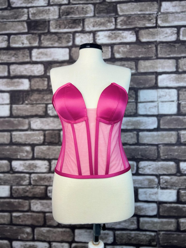 May include: A pink satin and mesh corset with boning and a sweetheart neckline.