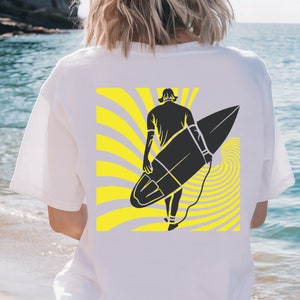 Peut inclure: T-shirt blanc avec un motif noir et jaune d'une personne faisant du surf. Le motif représente un surfeur stylisé avec une planche de surf et un motif en spirale jaune et gris.