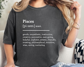 May include: A gray t-shirt with the word "Pisces" and its definition printed in white. The definition includes the traits of the Pisces zodiac sign: gentle, empathetic, instinctive, creative, perceptive, easy going, helpful, explorer, artistic, friendly, trusting, philosophical, intuitive, wise, caring, and nurturing.