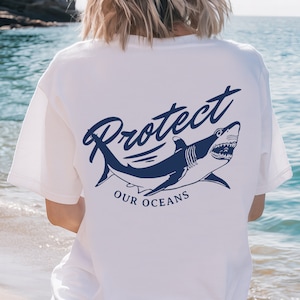 May include: White t-shirt with a blue shark graphic and the text "Protect Our Oceans".
