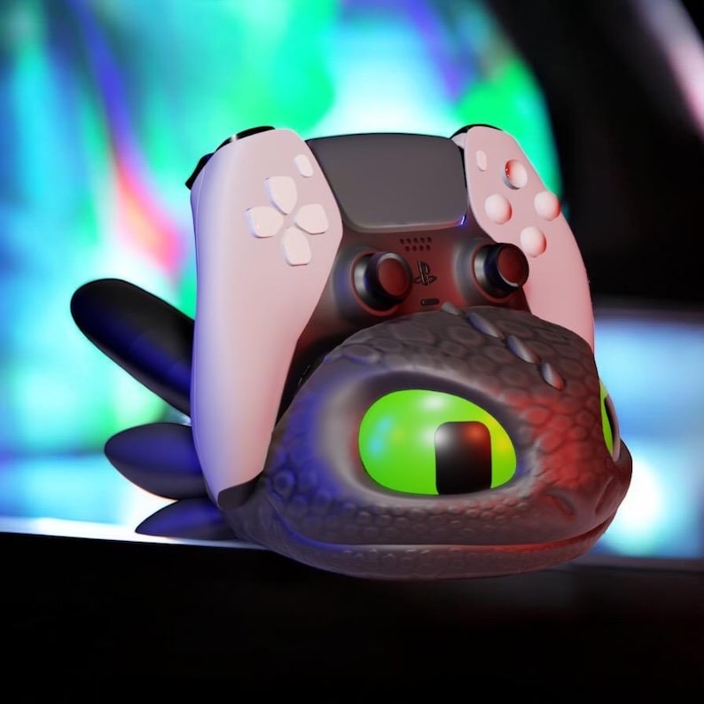 Pode incluir: Um controle PlayStation 5 preto e branco repousa sobre um suporte tem&aacute;tico de drag&atilde;o. O drag&atilde;o tem olhos verdes grandes e uma superf&iacute;cie texturizada detalhada. O controle tem detalhes brancos e bot&otilde;es pretos.