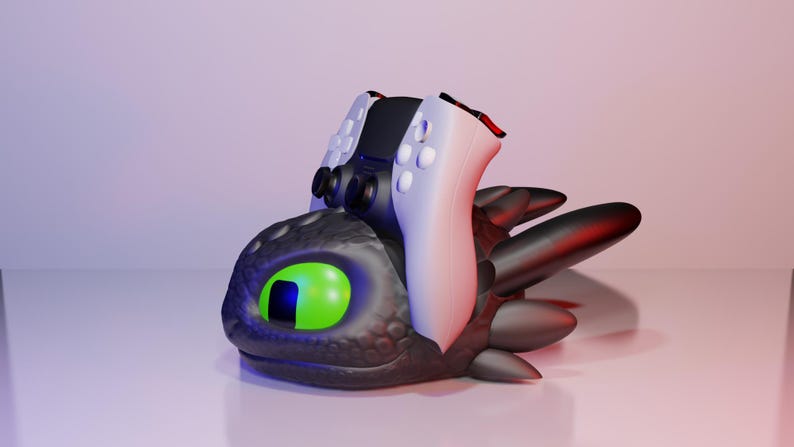 Pode incluir: Escultura estilizada de uma cabe&ccedil;a de drag&atilde;o preta com um olho verde e um controle de jogo preto e branco em cima. O drag&atilde;o tem reflexos vermelhos. O conjunto est&aacute; sobre uma superf&iacute;cie branca.