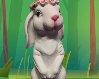 Könnte beinhalten: Eine weiße Hasenfigur mit rosa Nase und einem Kranz aus rosa Blumen. Der Hase sitzt mit zusammengelegten Pfoten. Der Hintergrund ist eine grün-blaue Waldszene.