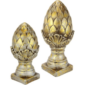 Puede incluir: Dos remates decorativos de piña dorada y plateada. El remate más grande mide 25 cm de alto y el más pequeño 15 cm de alto.